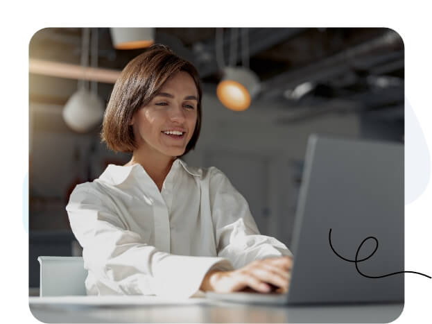 Una mujer concentrada en la pantalla de su computadora portátil en un entorno de oficina moderno.